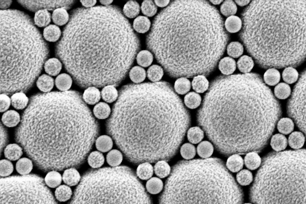 Die elektronenmikroskopische Aufnahme zeigt eine hexagonal angeordnete Struktur unterschiedlich großer Kugeln.